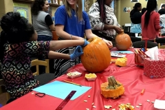 A tutor helps students with a pumpkin-based math activity